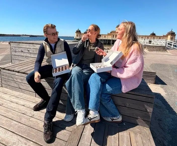 Ungdomar som njuter av Herrgårdstoppens kokosbollar i solen